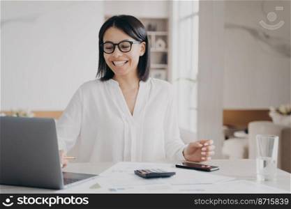 Happy female employee working at laptop got email with good news. Smiling businesswoman in glasses, looking at computer screen celebrates job promotion, successful deal, sitting at office desk.. Happy female employee working at laptop got email with good news. Job promotion, successful deal
