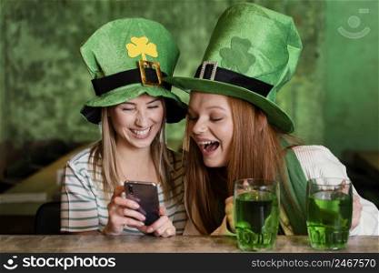 happy female friends celebrating st patrick s day together bar with smartphone