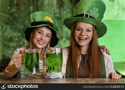 happy female friends celebrating st patrick s day together with drinks