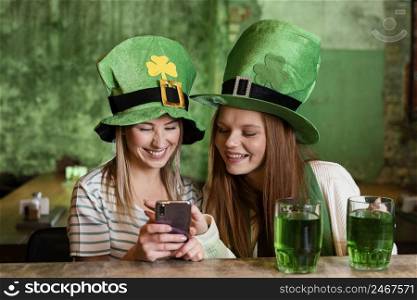 happy female friends celebrating st patrick s day together with smartphone bar