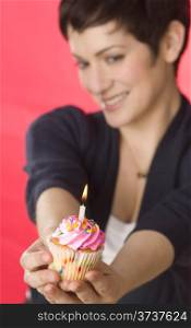 Happy Female Holds out Cupcake one Candle Celebrates Birthday