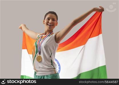 Happy female medalist celebrating victory with Indian flag isolated over gray background
