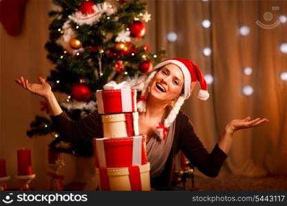 Happy female near Christmas tree with tower of present boxes &#xA;