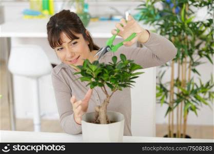 happy female nursery worker trimming plants