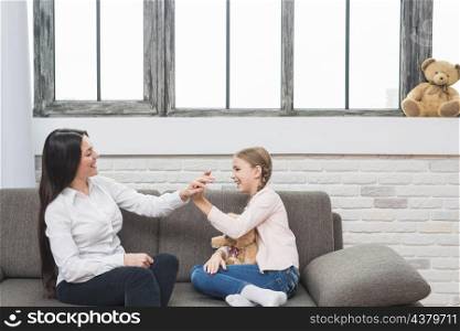 happy female psychologist giving high five little girl sitting sofa home