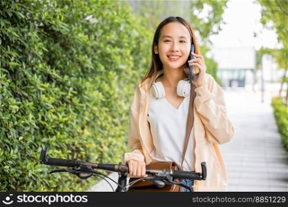 Happy female smiling walk at street with her bike on city road and cellphone with mobile phone, Asian young woman commute on smartphone with bicycle on summer in park countryside outdoor, travel