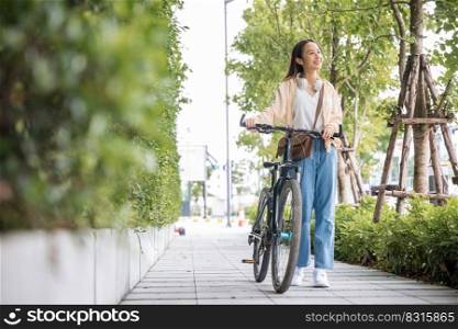 Happy female smiling walk down the street with her bike on city road, ECO environment, healthy holiday travel, Asian young woman walking alongside with bicycle on summer in park countryside outdoor
