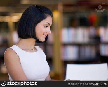 Happy female student at the library. Happy young female student sudying at the library