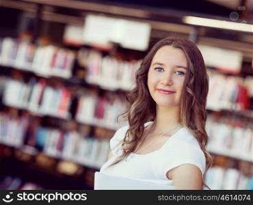 Happy female student holding books at the library. Happy young female student holding books at the library