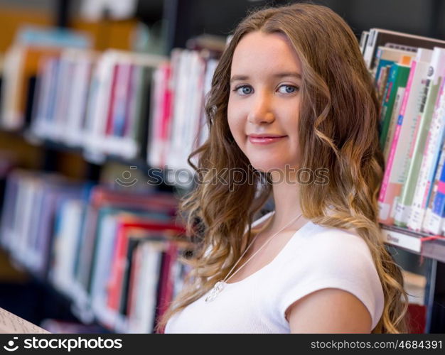 Happy female student holding books at the library. Happy young female student holding books at the library