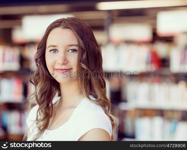 Happy female student holding books at the library. Happy young female student holding books at the library