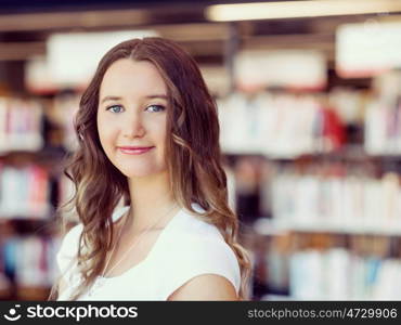 Happy female student holding books at the library. Happy young female student holding books at the library