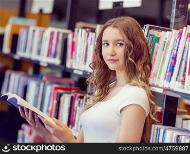 Happy female student holding books at the library. Happy young female student holding books at the library