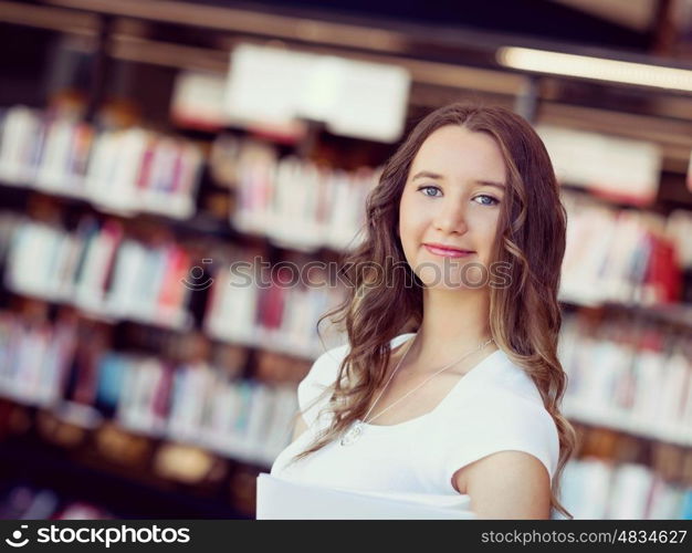 Happy female student holding books at the library. Happy young female student holding books at the library