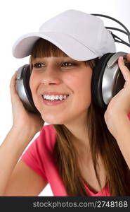 Happy female teenager enjoy music on white background, with headphones and baseball cap