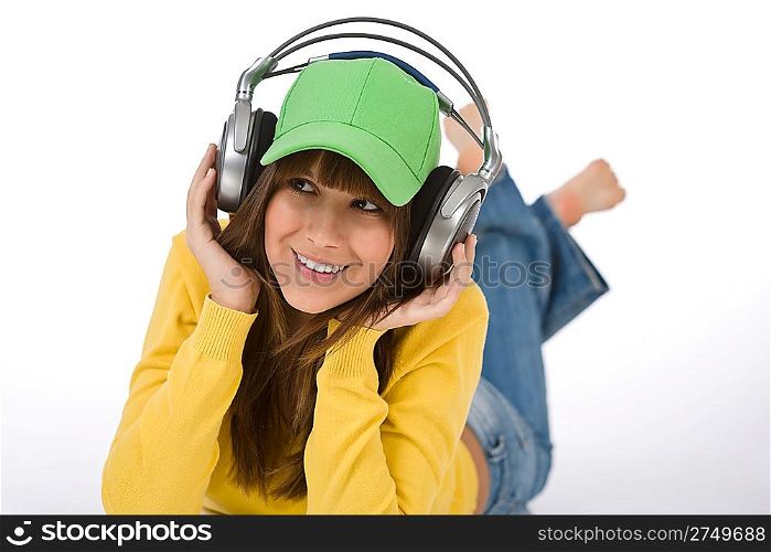 Happy female teenager enjoy music on white background, with headphones and baseball cap