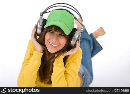 Happy female teenager enjoy music on white background, with headphones and baseball cap