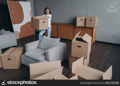 Happy female tenant holding box with personal things, standing in room. Woman renter or homeowner packing belongings for relocation to new home. Moving day, rented dwelling concept.. Happy female tenant holding box with personal things indoors. Moving day, rented dwelling concept