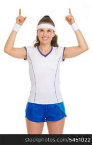 Happy female tennis player pointing up on copy space