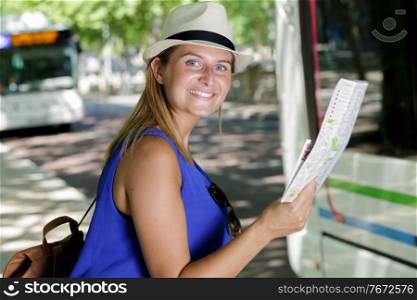 happy female tourist on location map to bus station vacation