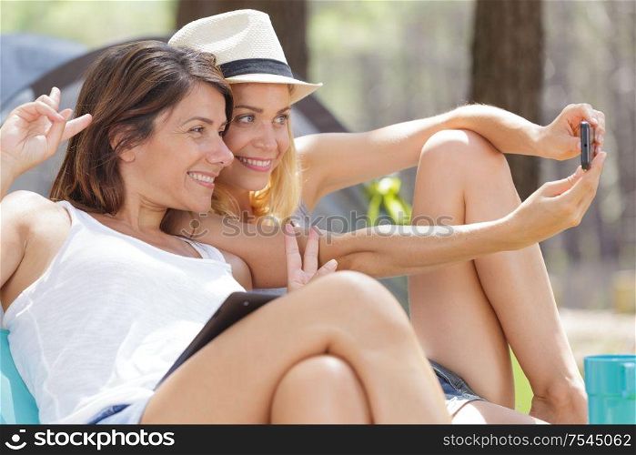 happy female tourists making selfie in forest