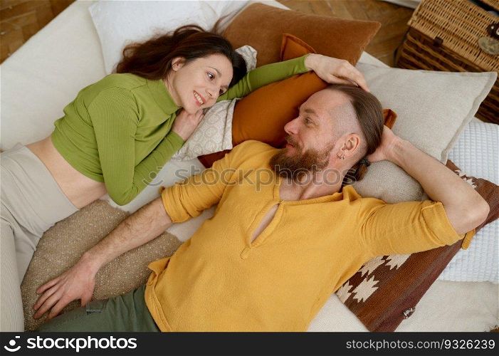 Happy fit sporty smiling man and woman rest after yoga training while lying on bed with pillows, overhead view. . Piece, love and relax concept. Happy fit sporty smiling man and woman rest after yoga training