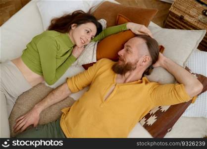 Happy fit sporty smiling man and woman rest after yoga training while lying on bed with pillows, overhead view. . Piece, love and relax concept. Happy fit sporty smiling man and woman rest after yoga training