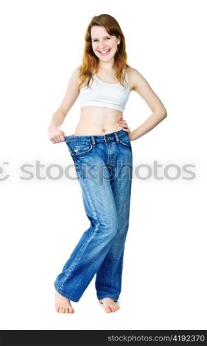 Happy fit young woman in loose old jeans after losing weight isolated on white
