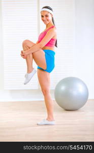 Happy fitness girl doing stretching exercises at living room&#xA;