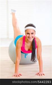 Happy fitness girl working out on fitness ball at living room&#xA;