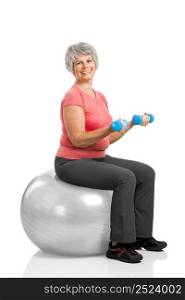 Happy fitness old woman lifting dumbbells while sitting over a PIlates ball