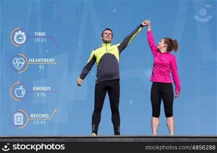 Happy fitness runner couple with arms raised up in winning gesture expression