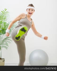 Happy fitness woman kicking in camera