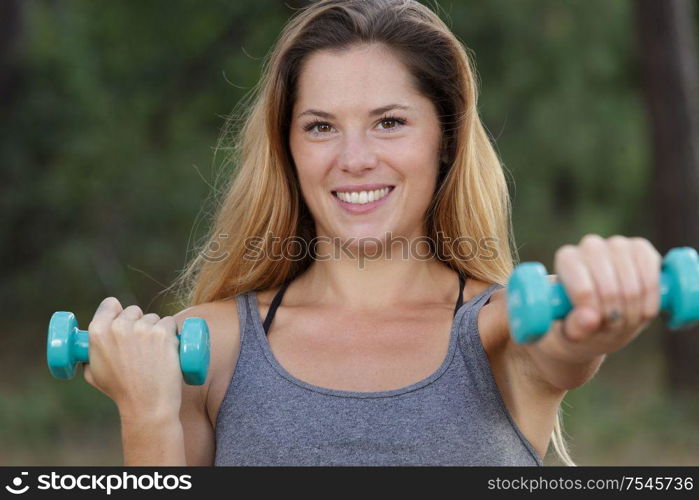 happy fitness woman lifting dumbbells and smiling