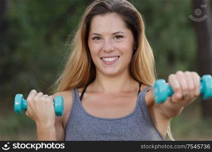 happy fitness woman lifting dumbbells and smiling