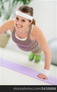 Happy fitness woman making push up exercise