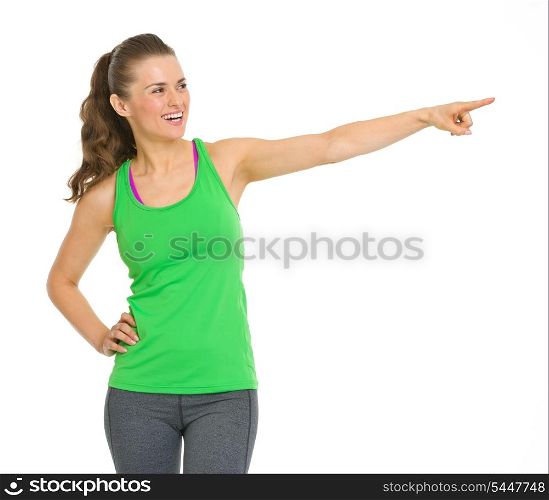 Happy fitness young woman pointing on copy space