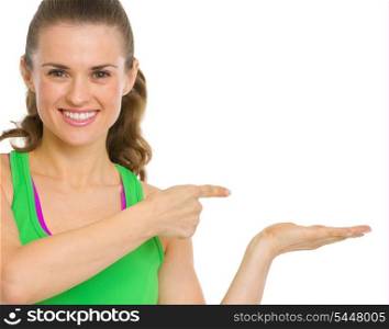 Happy fitness young woman presenting something on empty palm