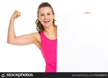 Happy fitness young woman showing biceps and blank billboard