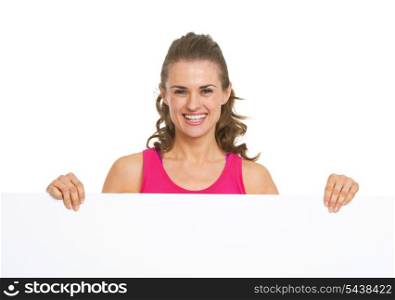 Happy fitness young woman showing blank billboard