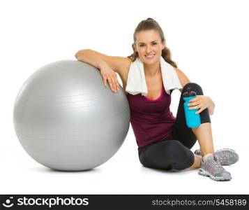 Happy fitness young woman sitting near fitness ball after workout