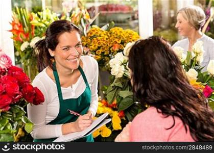 Happy florist writing flower shop talking customer woman