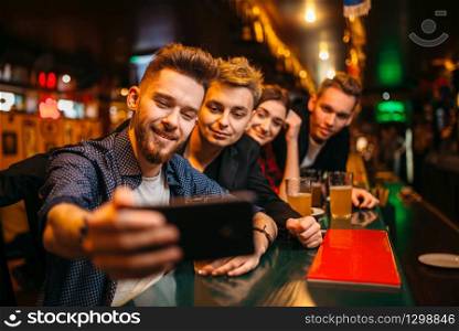 Happy football fans makes selfie on phone camera at the bar counter in a sport pub, victory celebration
