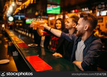 Happy football fans raised their glasses with beer at the bar counter in a sport pub, victory celebration