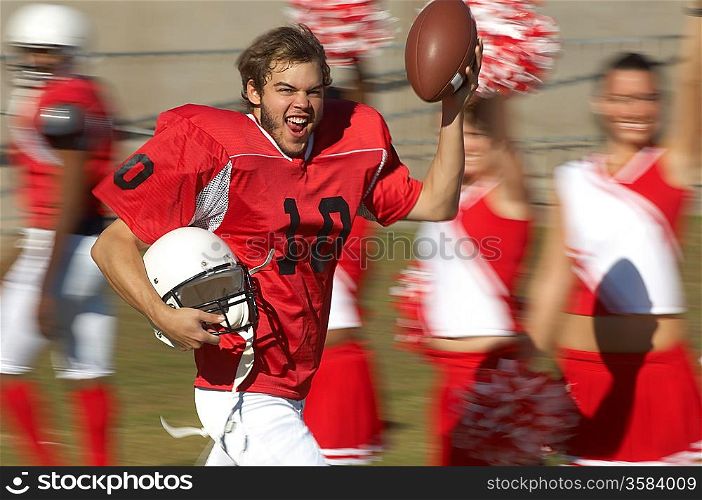 Happy Football Player Running by Cheerleaders