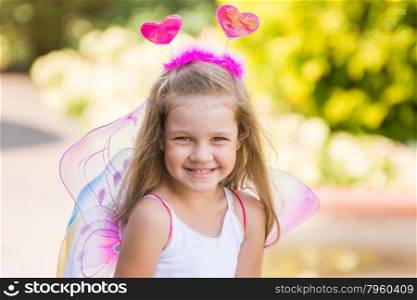 Happy four-year girl playing in fairy. happy four-year-girl in a fairy dress with wings on his back and antennae on his head