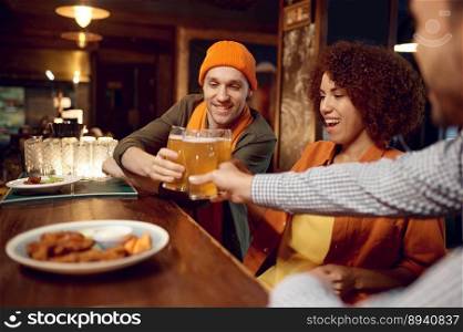 Happy friends drinking beer sitting at bar counter desk. Young people sharing impression about last game of favorite team while rest at sports pub. Selective focus. Happy friends drinking beer while rest sitting at bar counter desk