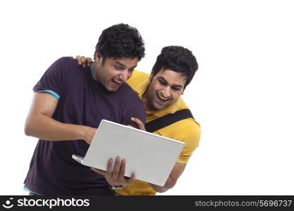 Happy friends laughing while using laptop