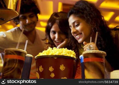 Happy friends looking at popcorn and soft drink