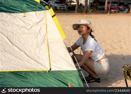 Happy friends pitch tent on sand at beach together to sea in holiday vacation time at sunset, Young Asian group woman and man in summer travel outdoor, Camping people outdoor lifestyle